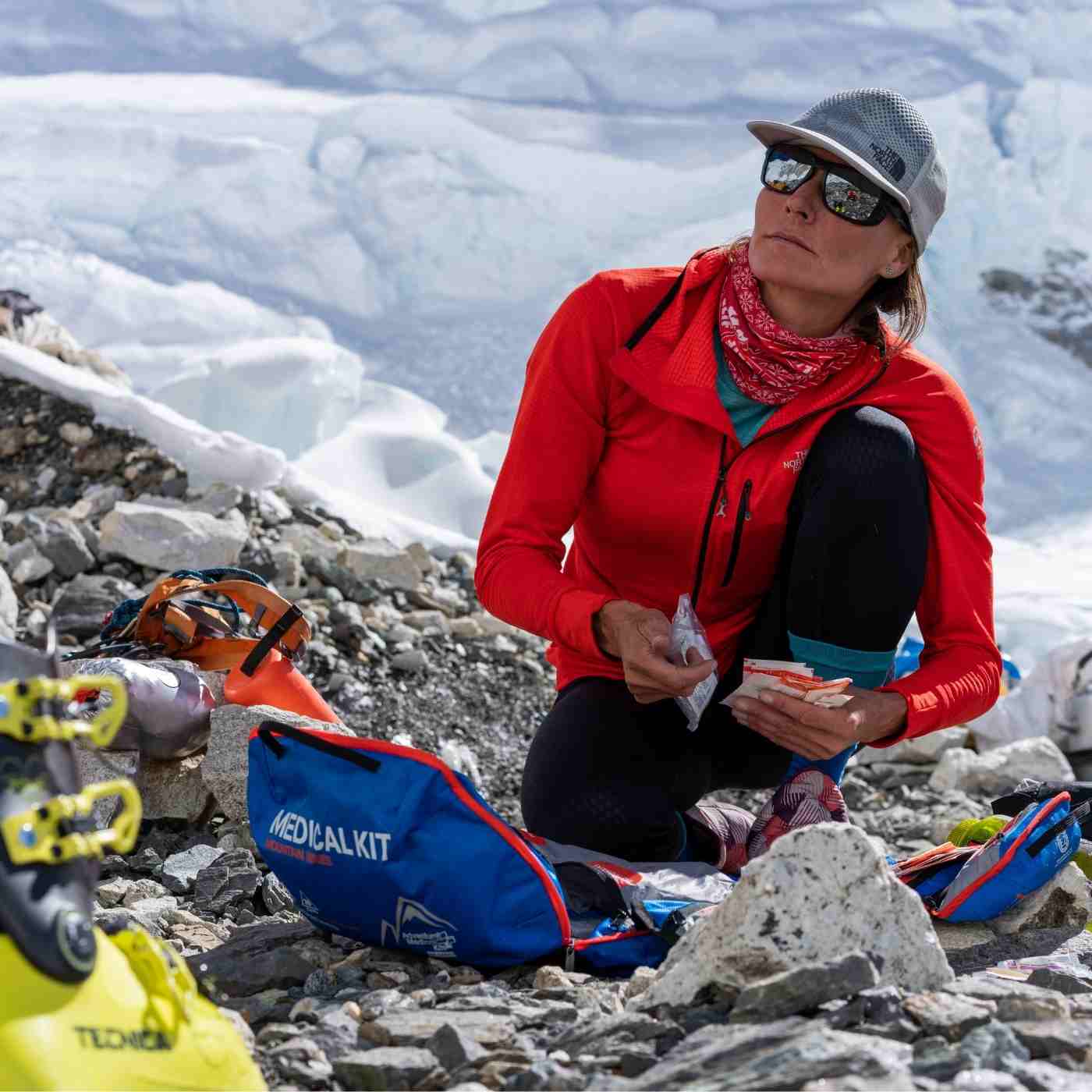 Mountain Series Medical Kit - Mountaineer woman removing kit contents on rocky ground and snow